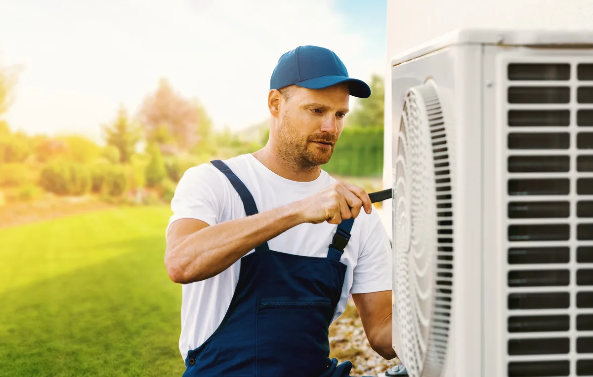 HVAC technician servicing an outdoor heat pump unit
