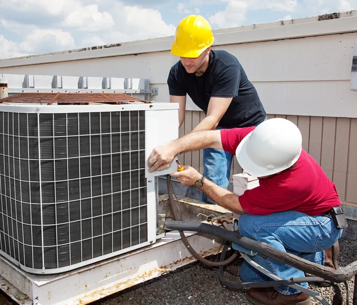 Technicians servicing a rooftop condenser on a commercial building