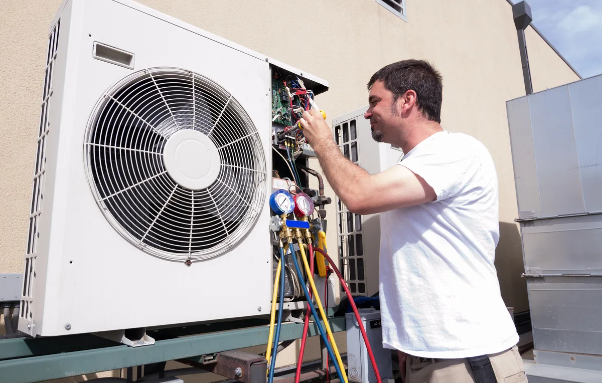 HVAC technician checking a ductless mini-split system with refrigerant gauges