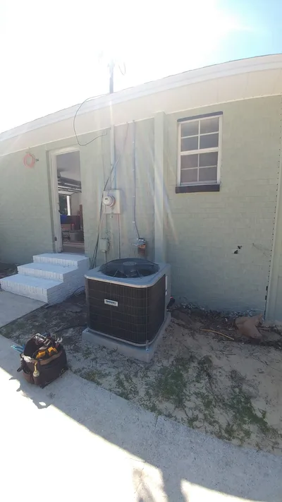 Residential heat pump unit on a concrete pad outside a Florida home
