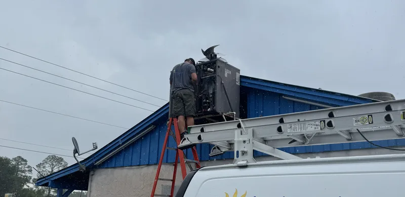 Lake Area Heating & Air technician servicing a rooftop unit above a company van